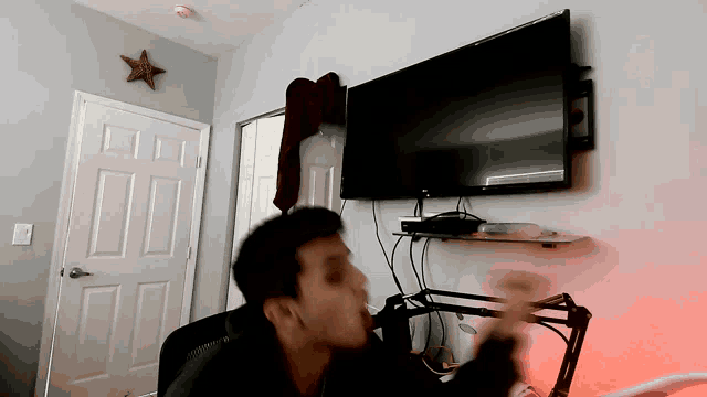 a man is sitting in front of a television in a bedroom