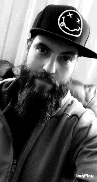 a man with a beard is wearing a hat with a smiley face on it