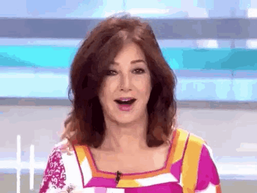 a woman with a surprised look on her face is wearing a colorful top