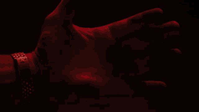 a man wearing a watch holds out his hand with a red light coming out of it