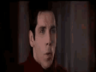 a close up of a man 's face in a dark room making a funny face .