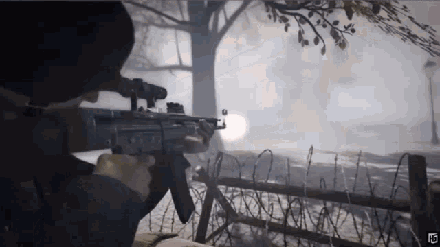 a man is holding a gun in front of barbed wire fence