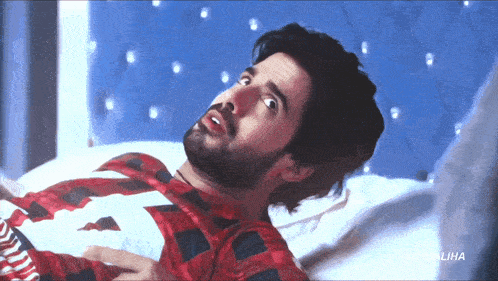 a man with a beard is laying on a bed with the word malika on the bottom