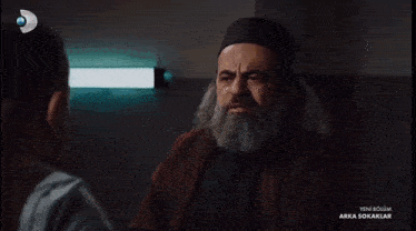 a man with a beard is on a tv screen that says yeni bolum arka sokaklar