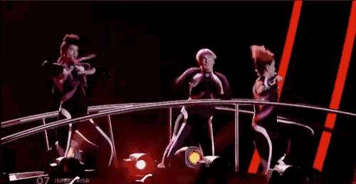 a group of people are dancing on a stage with red lights .