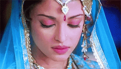 a close up of a woman 's face wearing a blue and gold dress and jewelry .