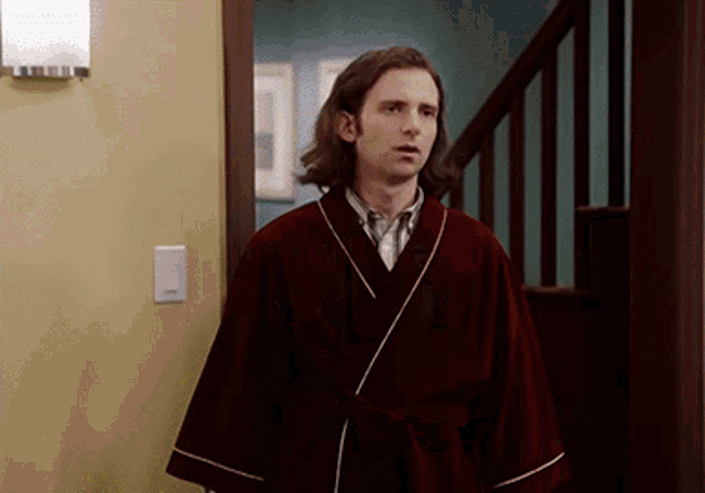 a man in a robe is standing in a doorway next to stairs