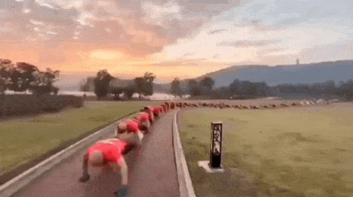 a group of people are doing push ups on a track in a field .