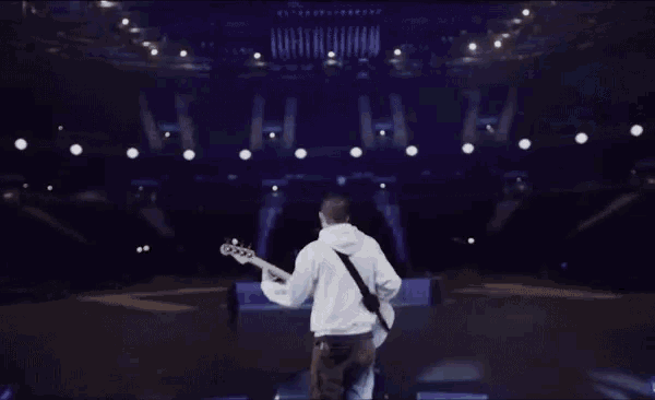 a man playing a guitar on a stage with a purple background