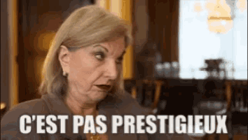 a woman is sitting at a table with the words `` c ' est pas prestigieux '' written on the screen .
