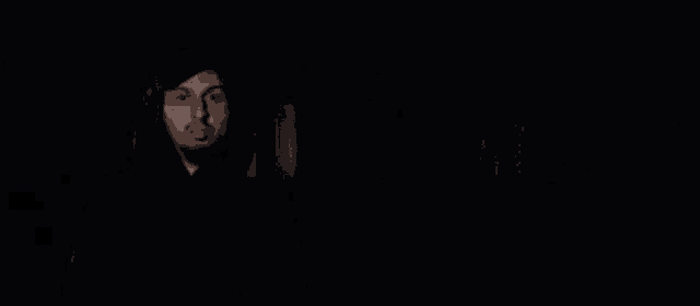 a man in a black hoodie stands in front of flames