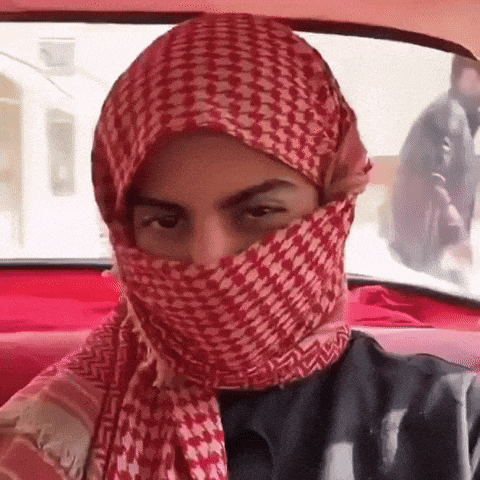 a man wearing a red scarf covering his face is sitting in a car