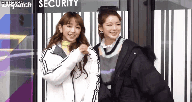two young women are standing next to each other in front of a building that says security .