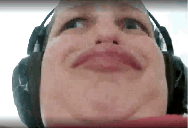 a close up of a person wearing headphones and making a funny face