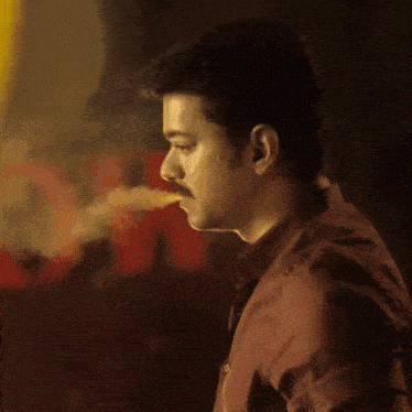 a man with a mustache and a red shirt is looking down at something .