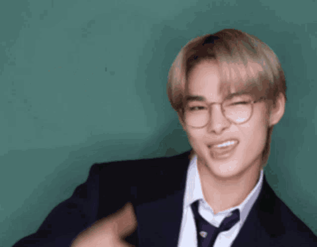 a young man wearing glasses and a suit and tie is making a funny face .