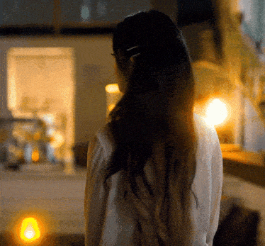 a woman 's back is shown in a blurry photo with a yellow light in the background