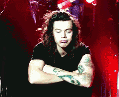a man with long hair is sitting with his arms crossed and his eyes closed