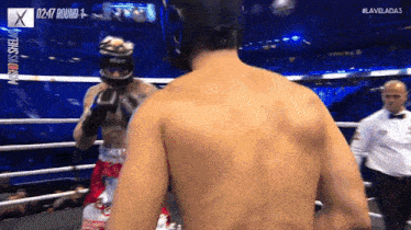 a man in a boxing ring is wearing a helmet while another man looks on