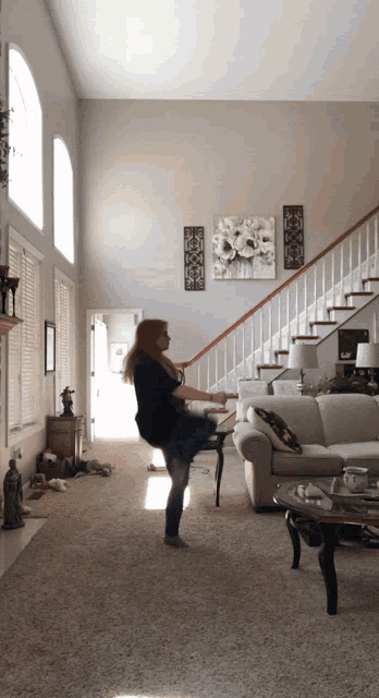 a woman is standing in a living room in front of a white couch and stairs