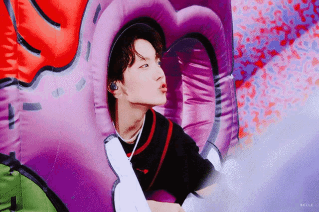 a young man is sitting in a purple heart shaped inflatable .