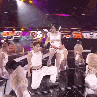 a group of people are dancing on a stage and one of them is kneeling on the floor