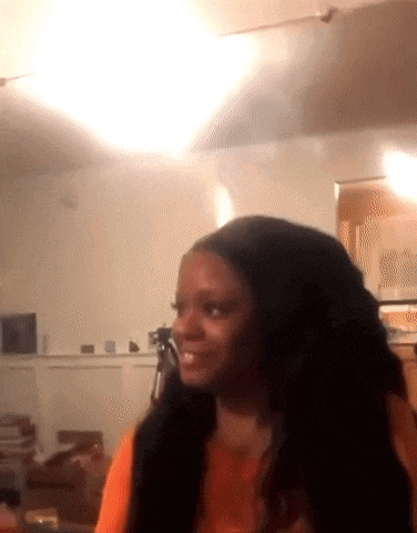 a woman with long hair is sitting in a living room with a camera .