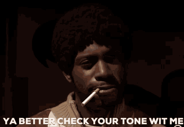 a man is smoking a cigarette and saying ya better check your tone wit me .