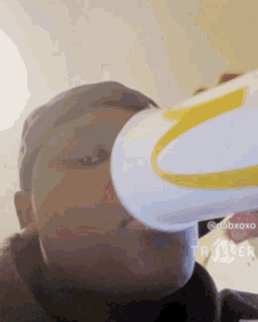 a man is drinking from a white cup with a yellow m on it