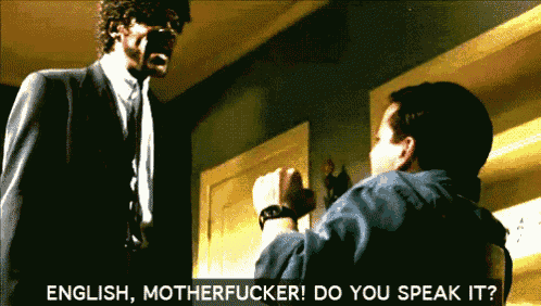 a man in a suit and tie is talking to another man in a room with the words english motherfucker do you speak it below him