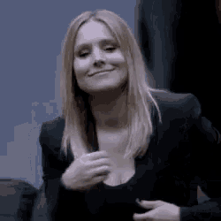 a woman in a black jacket is smiling while holding her breast .