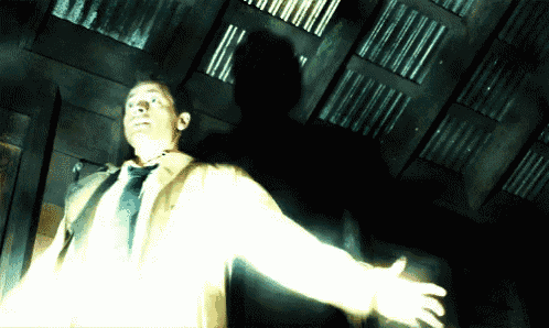 a man in a suit and tie is standing in the dark with his arms outstretched