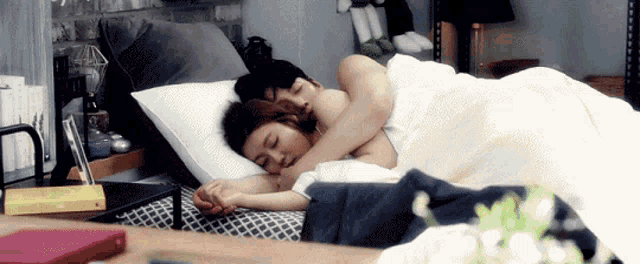 a man and a woman are sleeping on a bed holding hands