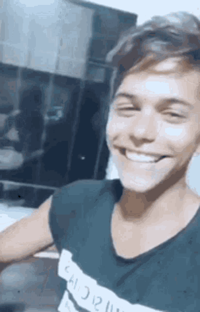 a young man in a black shirt is smiling for the camera .
