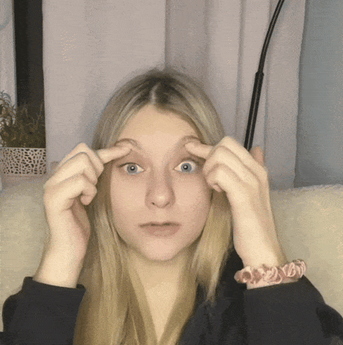 a girl with a pink bracelet on her wrist is touching her eyes