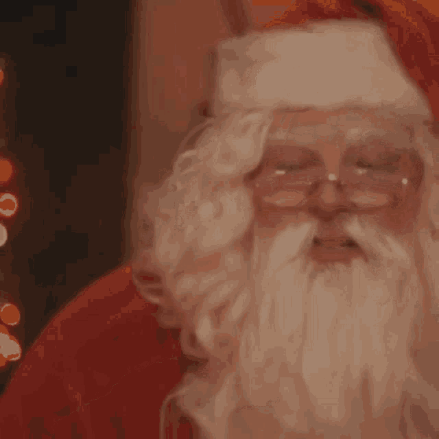 a close up of santa claus 's face with glasses and a beard