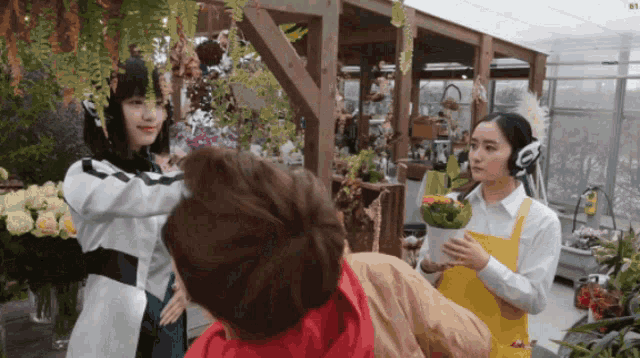 a woman in a yellow apron holds a potted plant