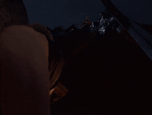 a person is standing in a dark room with a pillar in the background