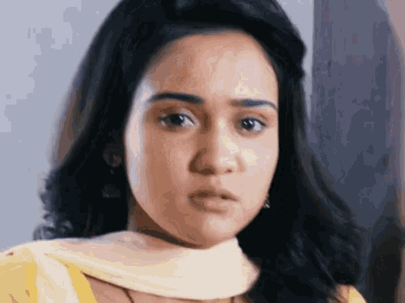 a close up of a woman 's face wearing a yellow top