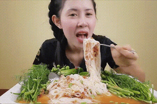 a woman is eating noodles with a fork and spoon