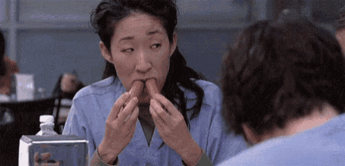 a woman is eating a hot dog while sitting at a table .