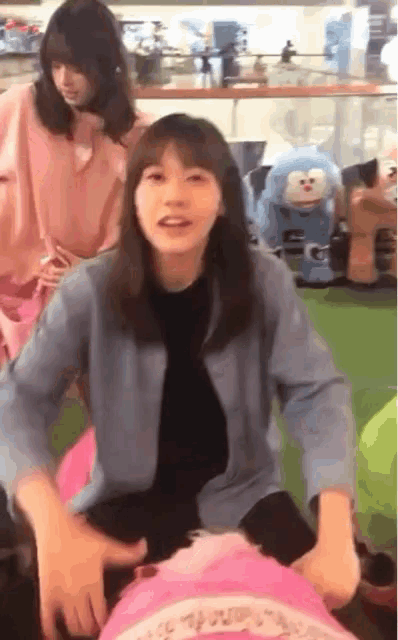 a woman in a blue jacket is sitting on a pink blanket