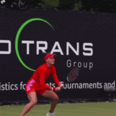 a woman in a red dress is holding a tennis racquet in front of a sign that says co rans group