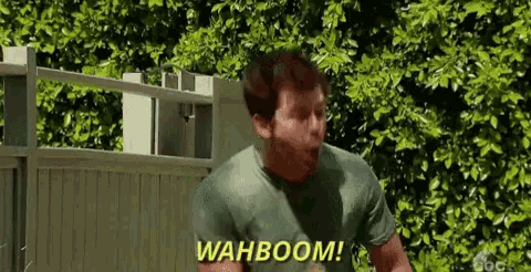 a man in a green shirt is standing in front of a fence .