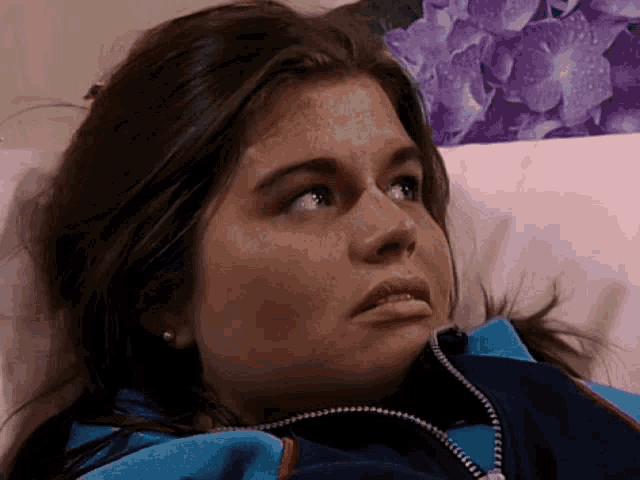 a woman is laying on a bed with a purple flower in the background