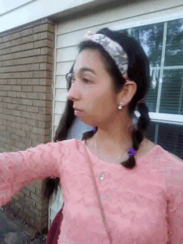 a girl with pigtails and a headband is wearing a pink top