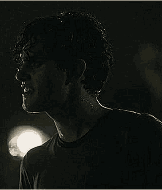 a close up of a man 's face in the dark with sweat coming out of his neck .