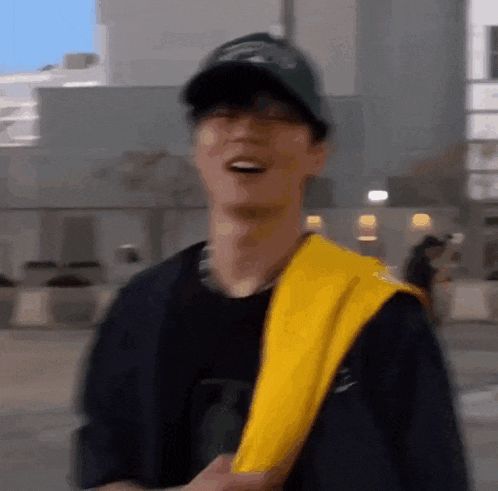 a man wearing a baseball cap and a yellow scarf around his neck is smiling .