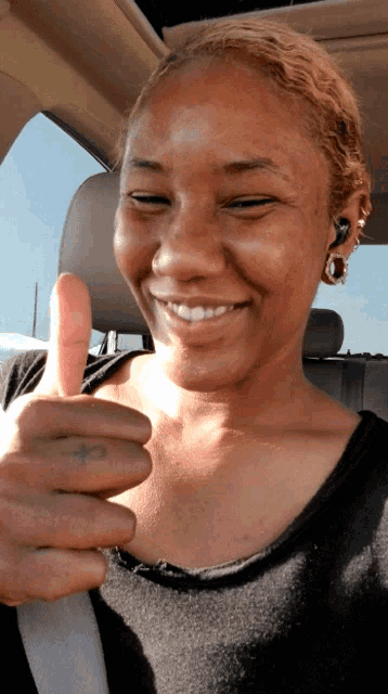 a woman is giving a thumbs up in a car