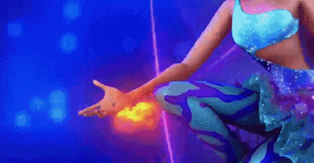 a woman in a blue dress is holding a glowing object in her hands .